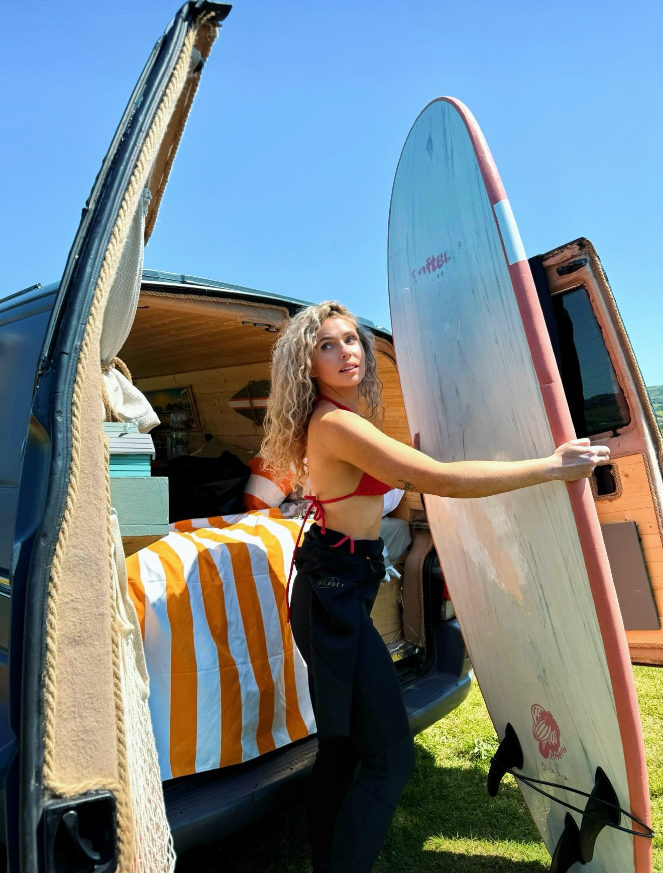 Lana lifting a surfboard from the original Storky campervan