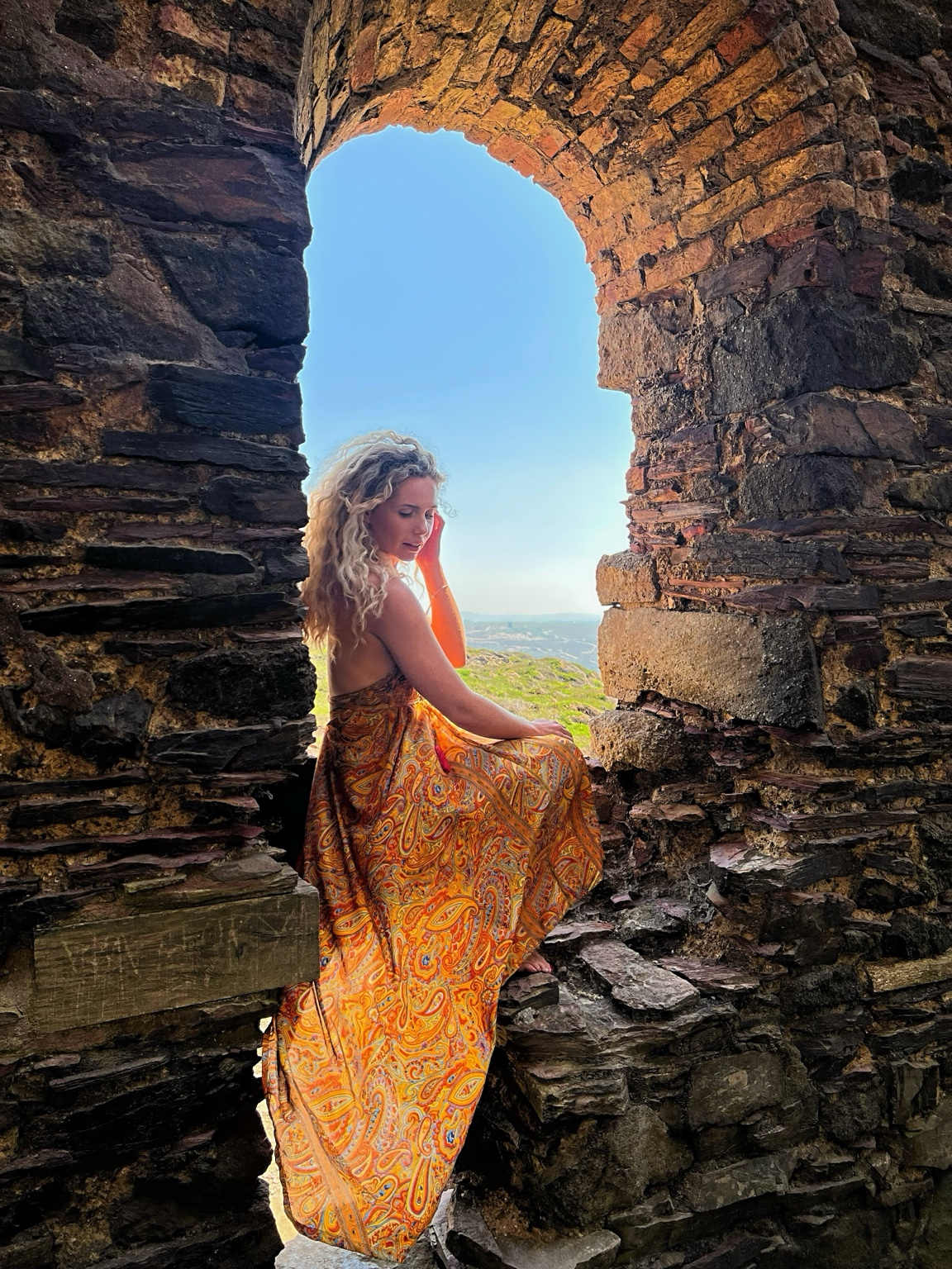 Lana sitting in a stone archway during an adventure