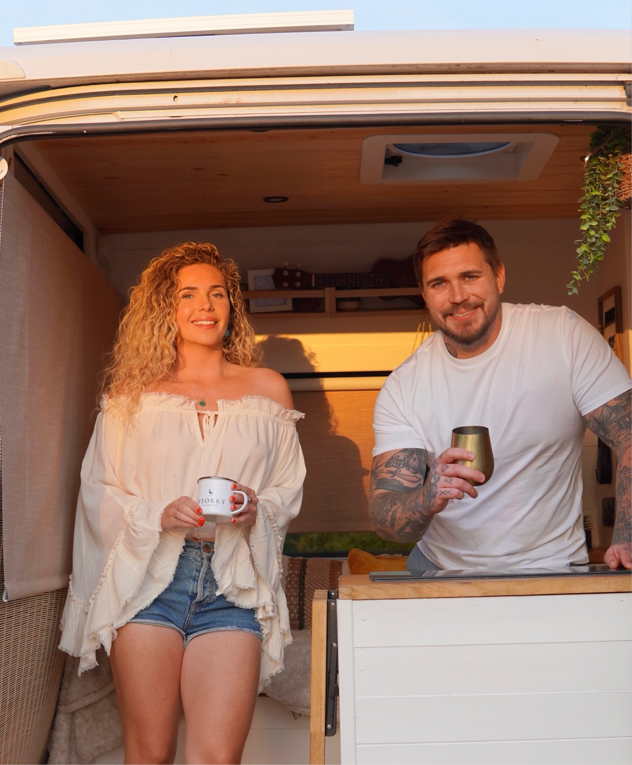 Lana and Tomm smiling together in the doorway of their campervan