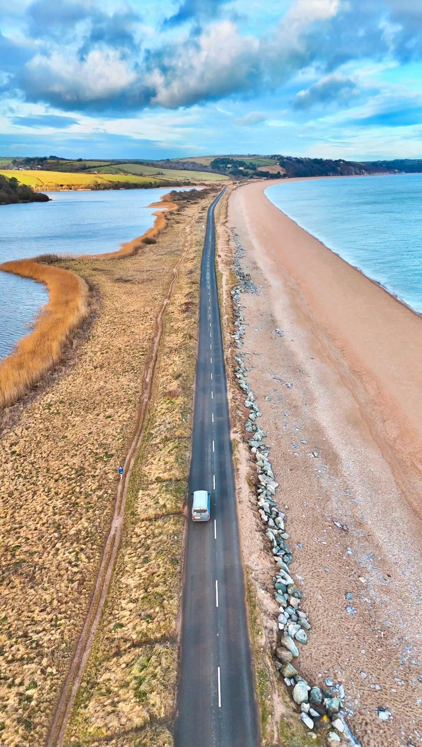 Storky driving along a coastal road between the beach and an estuary