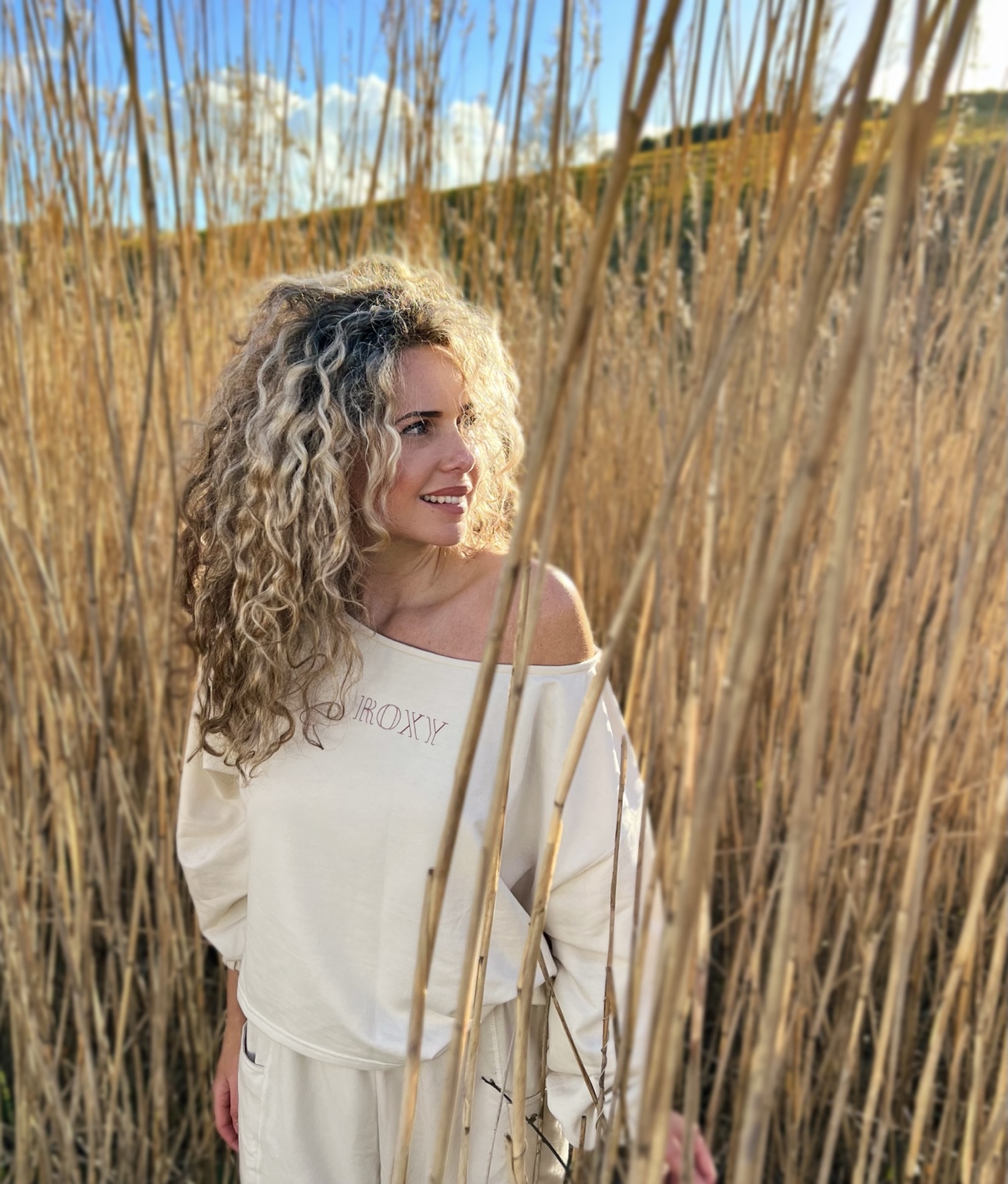 Lana standing among tall reeds in warm evening light